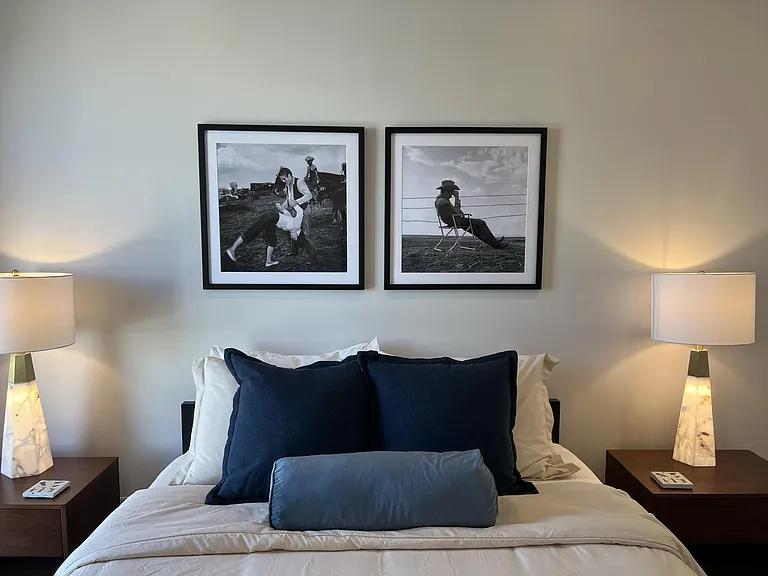 Primary bedroom showcases new artwork, a queen bed, floor-to-ceiling windows for natural light, and an attached bathroom for added convenience.