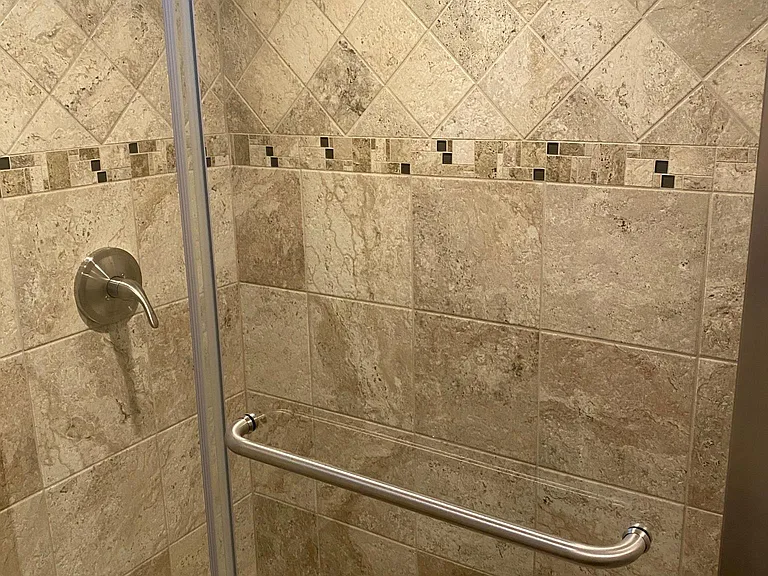 Downstairs bathroom has very large spacious shower with beautiful tile work.