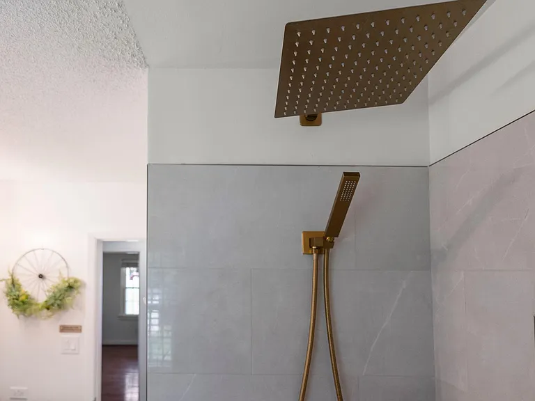 Walk-in shower with large rainfall showerhead, handheld sprayer, and tiled surround for easy everyday use.