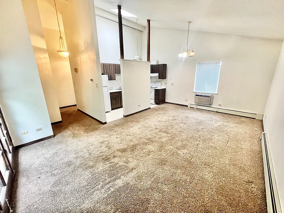 Inviting open-concept living area featuring plush carpeting, abundant natural light, and a cozy kitchen nook perfect for comfortable modern living.