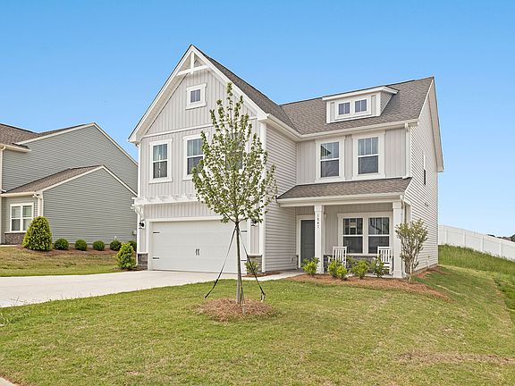 A white house with a gray roof is sitting on top of a grassy hill.