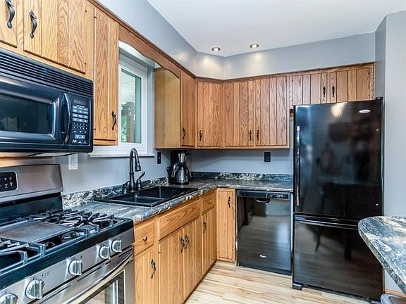 This cozy kitchen has a 5-burner gas oven, deep granite-composite type double bowl sink with gooseneck extension faucet, a pantr