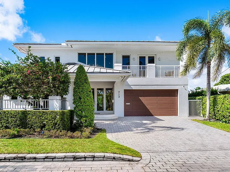Step into elegance with a grand entryway framed by lush greenery and sophisticated architecture.