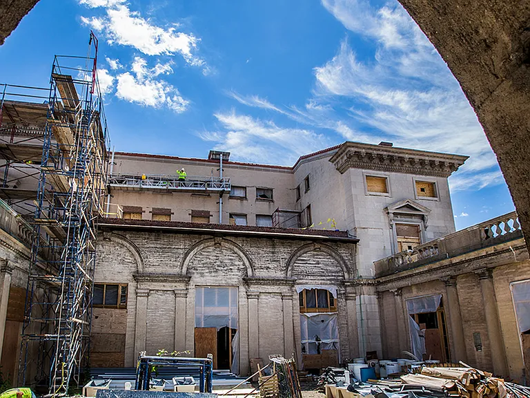 Before: Exterior of building shot through an archway during renovation process