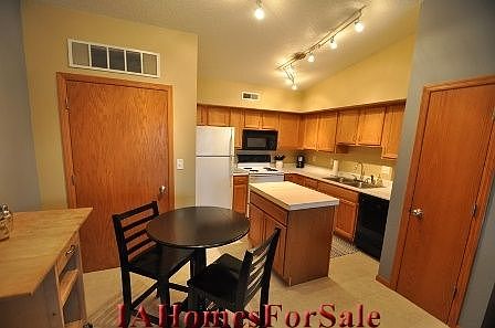 This large kitchen has an island with a butcher block countertop and new track lighting.  It has vaulted ceilings, new 16 inch tile floor, and is open to the living room.  Kitchen also has food pantry and utility closet with water softener.