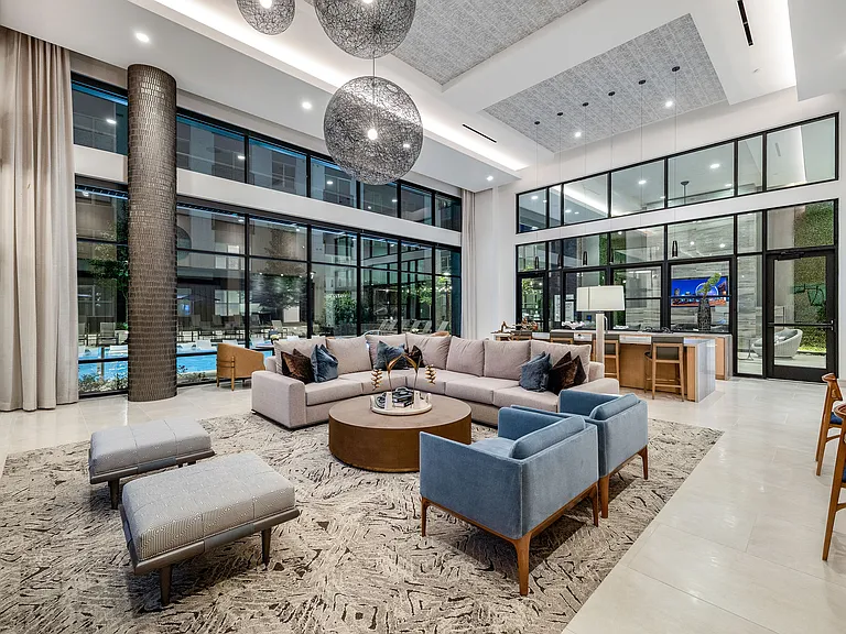 Luxurious modern lounge with a spacious open layout, featuring stylish seating, large windows, and elegant lighting fixtures that create a warm and inviting atmosphere.