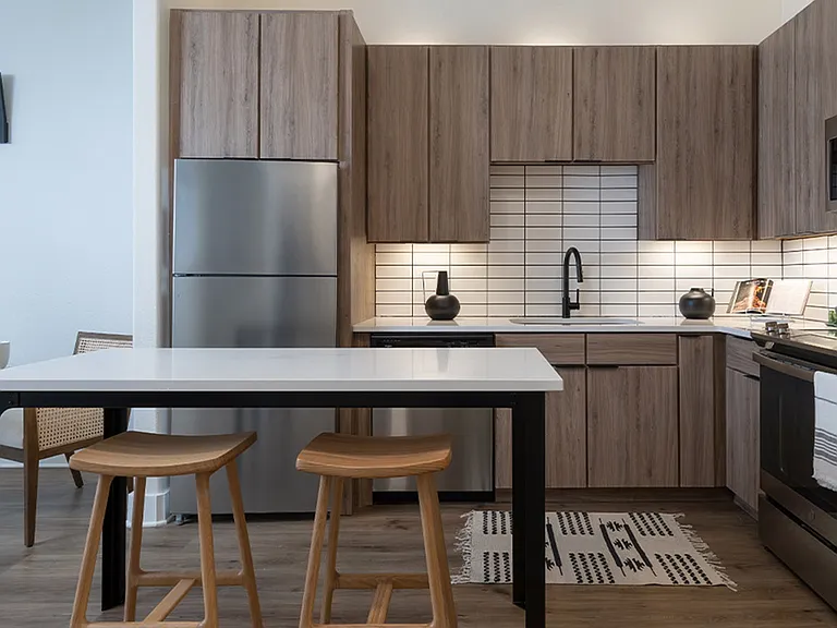 Apartment kitchen with stainless steel appliances, quartz countertops and wood-style flooring.