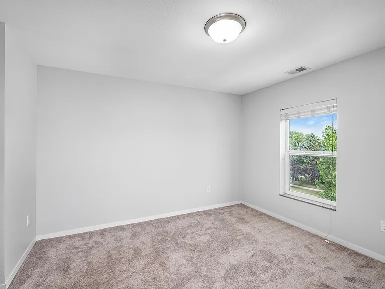 Bright and airy room with plush carpeting, fresh white walls, and a large window offering scenic green views. Bright and airy room with plush carpeting, fresh white walls, and a large window offering scenic green views.
