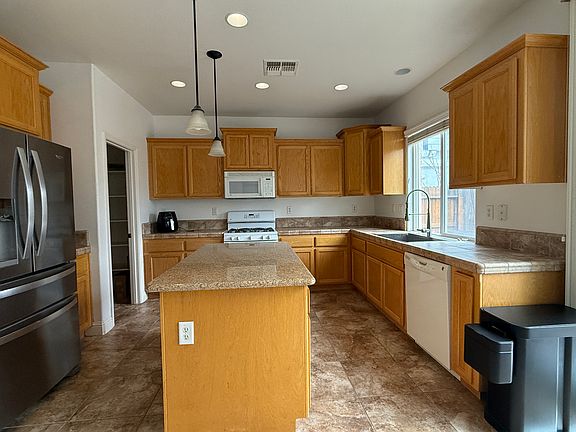 Tile floor kitchen with granite island and tile floor and counter top, built-in microwave and dishwasher, a large pantry