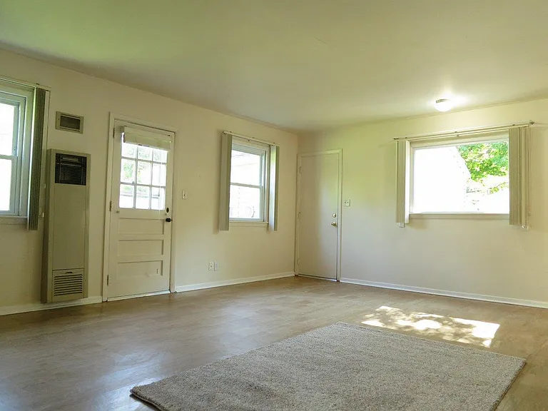 Second living room on south side. Backup gas heater built into the wall next to the door in case of an emergency. Tile flooring and lots of windows.