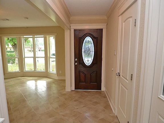 Entry with a beveled glass front door, tile flooring and crown molding.