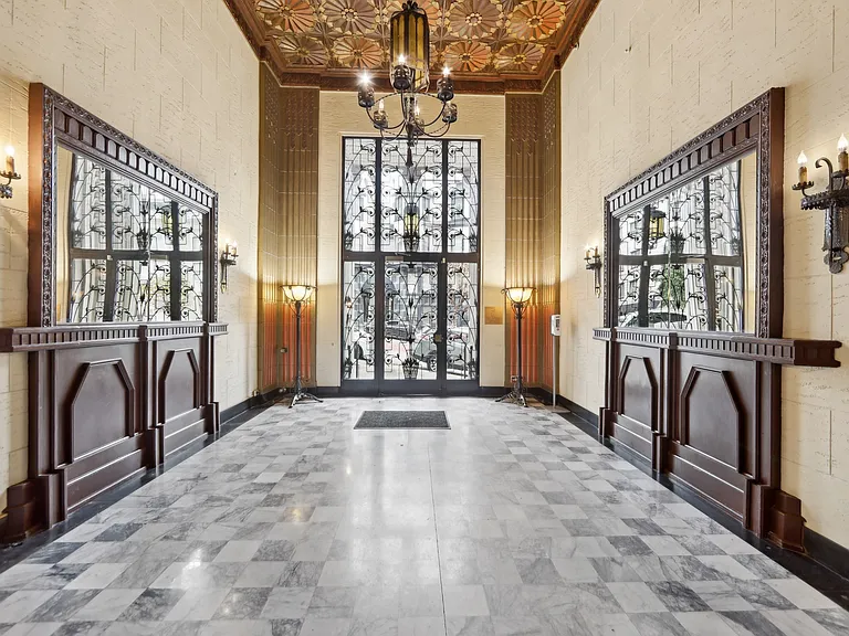Grand entrance to a building, featuring a large, ornate chandelier suspended from the ceiling, casting a warm glow over the space
