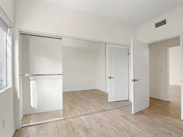 Large Bedroom with Full-Size Mirrored Closet, Vinyl Flooring, and Window