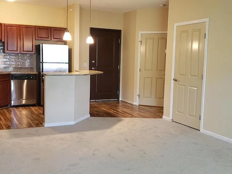 Condo entryway walks into this open floor plan showing the new laminate flooring throughout the kitchen and into the hall with laundryroom to the left and guest closet on the right