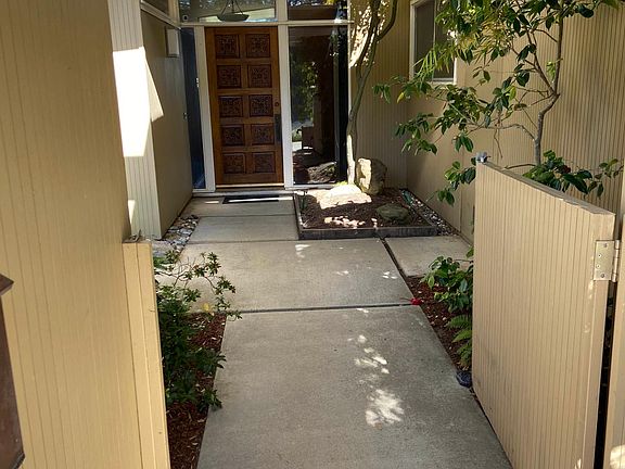 The front gate opens to a welcoming entry and a mature, low-maintenance garden.