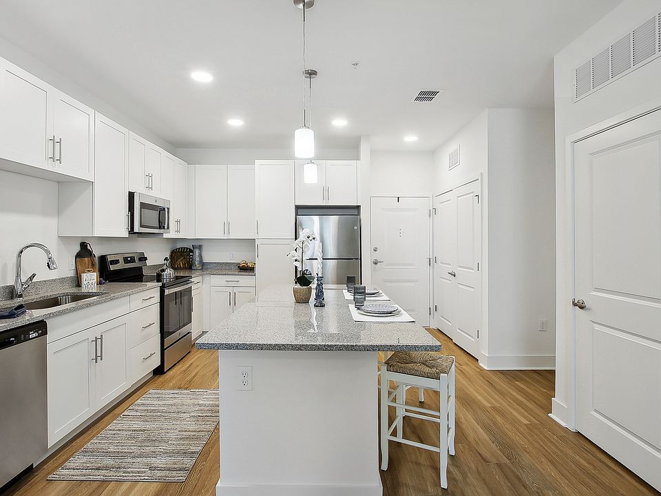 Modern kitchen with sleek white cabinetry, stainless steel appliances, and elegant countertop island with seating.