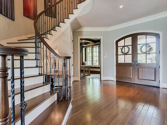 Dramatic Curved Staircase is adorned with a Handmade Railing and Wrought Iron Spindles. The Custom Oak Floors with beveled edges were carefully set, hand soaked.