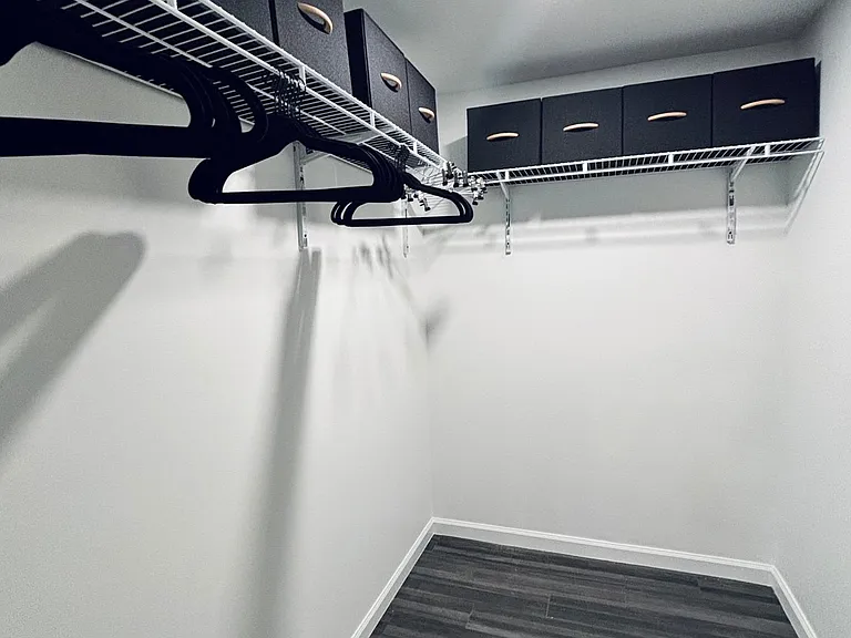 Walk-in storage closet with wire shelving, hanging rods, and labeled bins to keep clothing and gear neatly organized.
