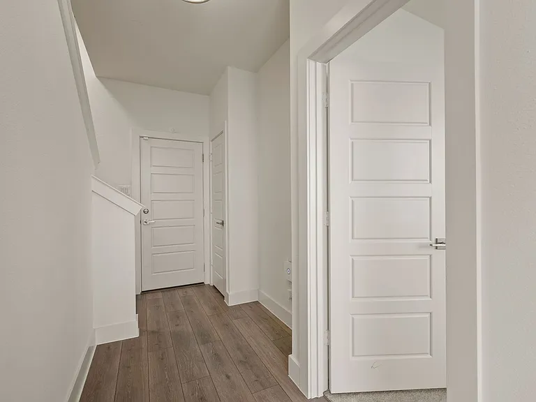 Entry hallway with Bedroom #1 on the right, garage door straight ahead, and stairs to the second floor on the left.
