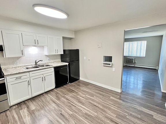 Modern kitchen with sleek appliances and granite countertops, leading into a bright and spacious living area with stylish flooring.