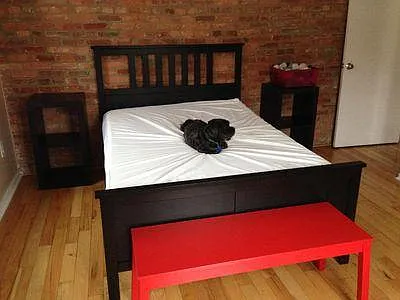 Previous tenant with picture of larger bedroom with bed on opposite brick wall in front of the door.