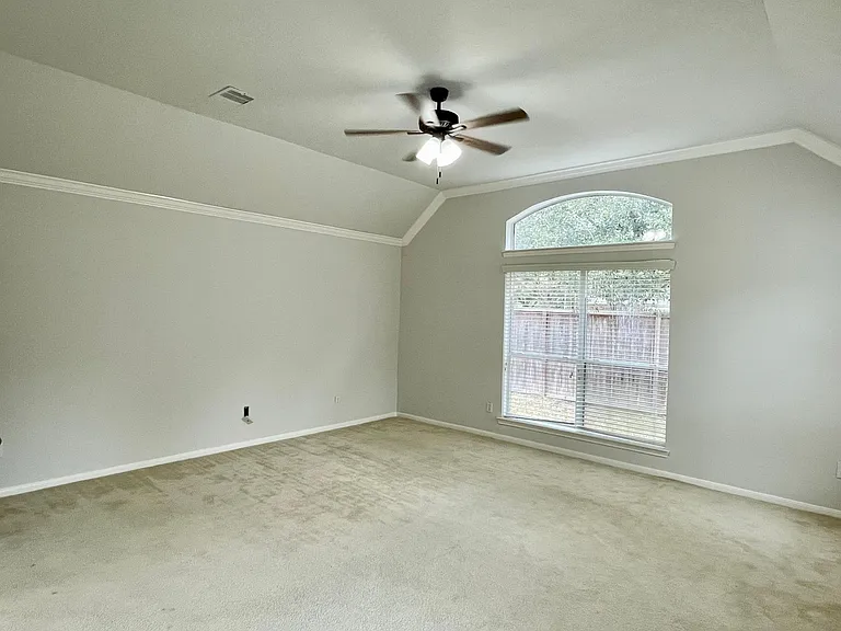 Generously sized primary bedroom with crown molding, sitting area and large windows.