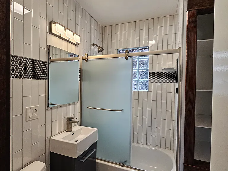 Mirrored vanity that opens to storage and under sink cabinet with additional storage.