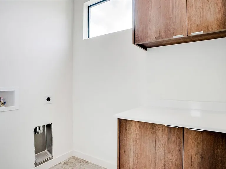 Utility room featuring wood-finish cabinetry, a crisp white countertop, and a high transom window