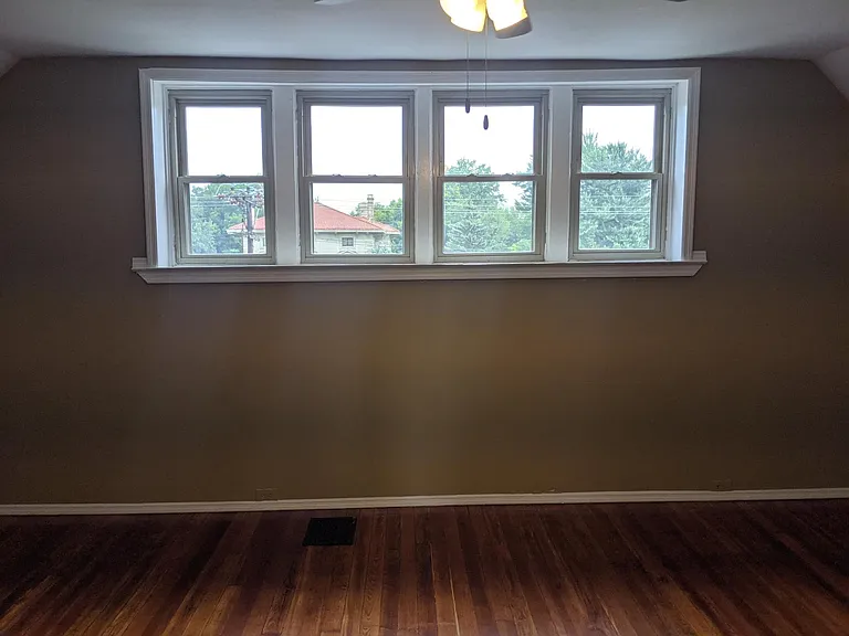 Large third floor bedroom with newly refinished hardwood floors.