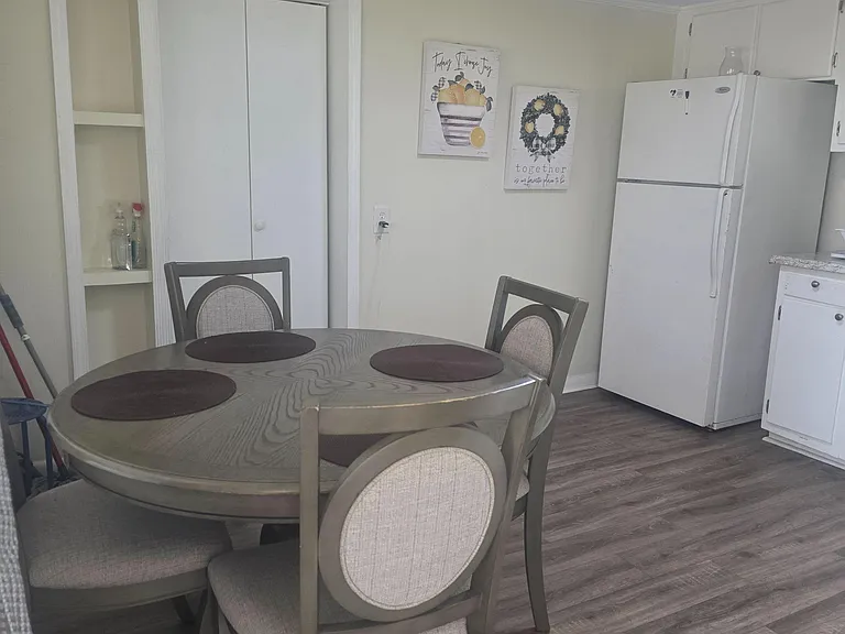 Eat-in kitchen nook with a round dining set, adjacent cabinetry, and a full-size refrigerator for everyday convenience.