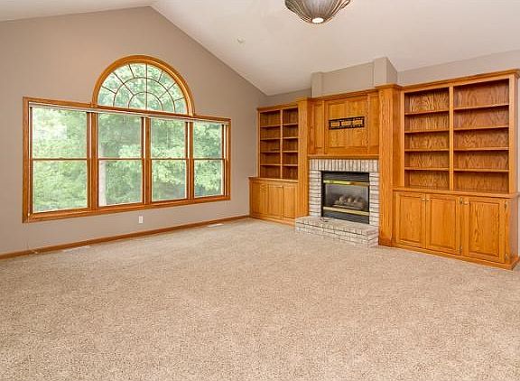 Main floor great room with custom built in, transom windows, vaulted ceiling and gas fireplace.