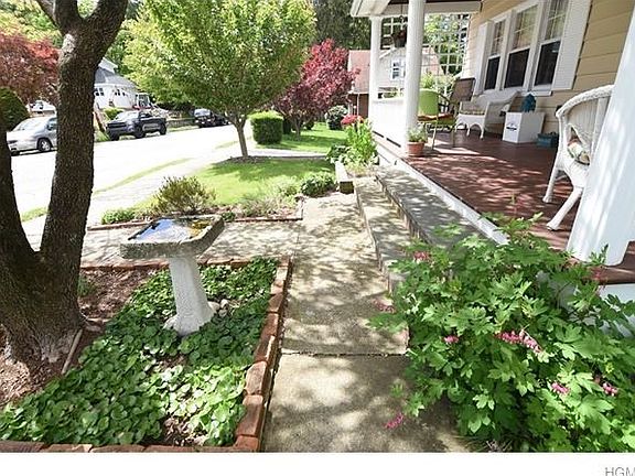 Shady front porch overlooks the low-traffic street and perennial garden and flowering trees