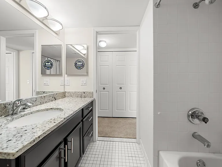 Modern bathroom with large vanity mirror and tub/shower at Lakeside Village Apartments in Clinton Township, MI