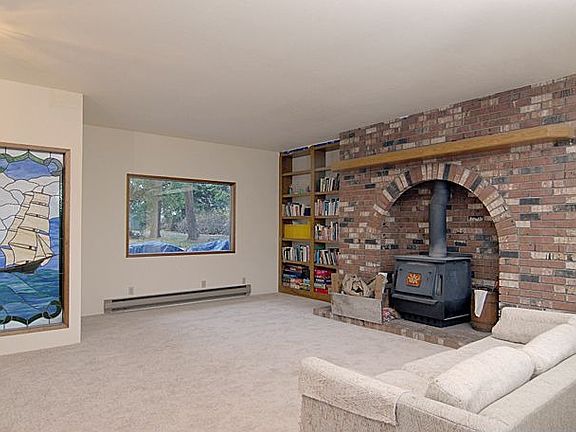 Huge living room with wood stove, stained glass window and new carpet.