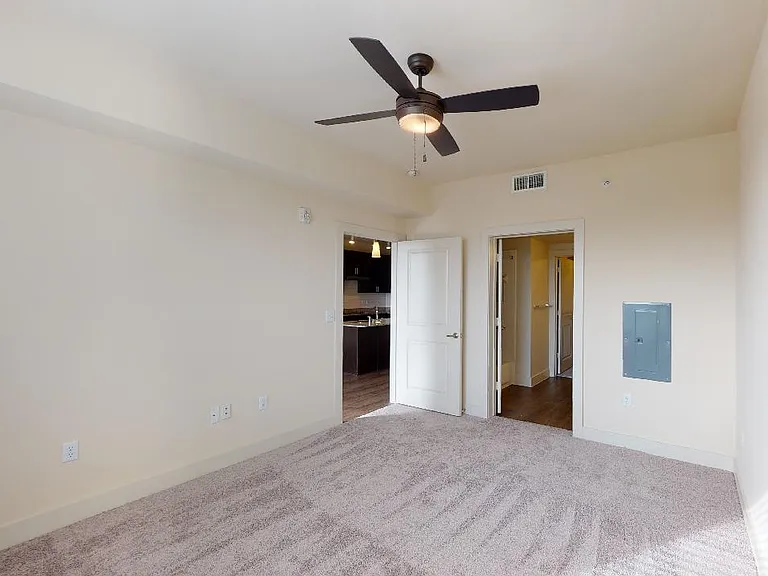 Spacious apartment bedroom with attached bathroom and plush carpet flooring.