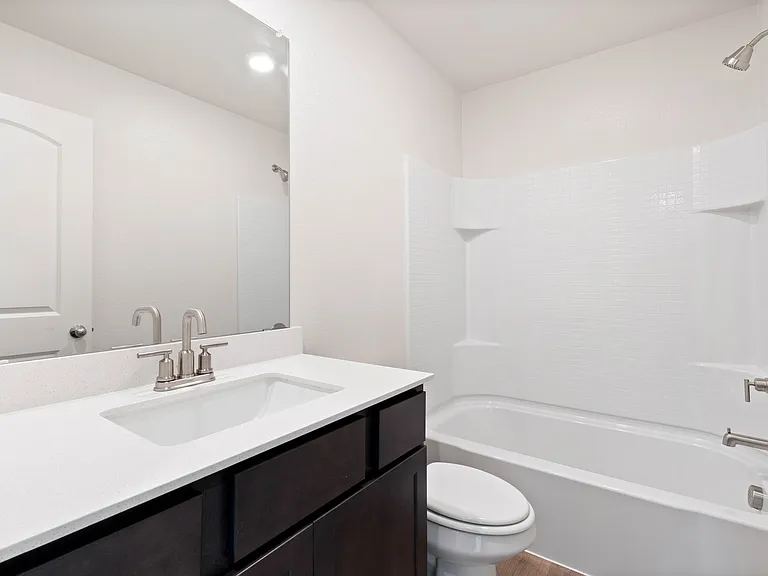 The secondary bathroom has a large vanity space and a shower-tub combo.