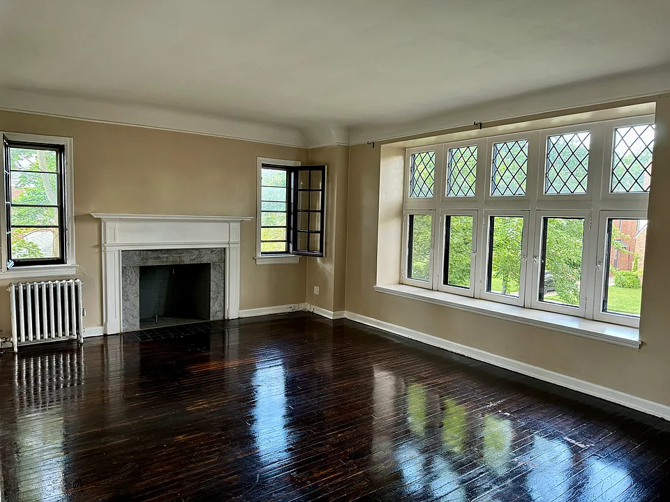 Large living room with hardwood floors, decorative fireplace, and oversized windows.