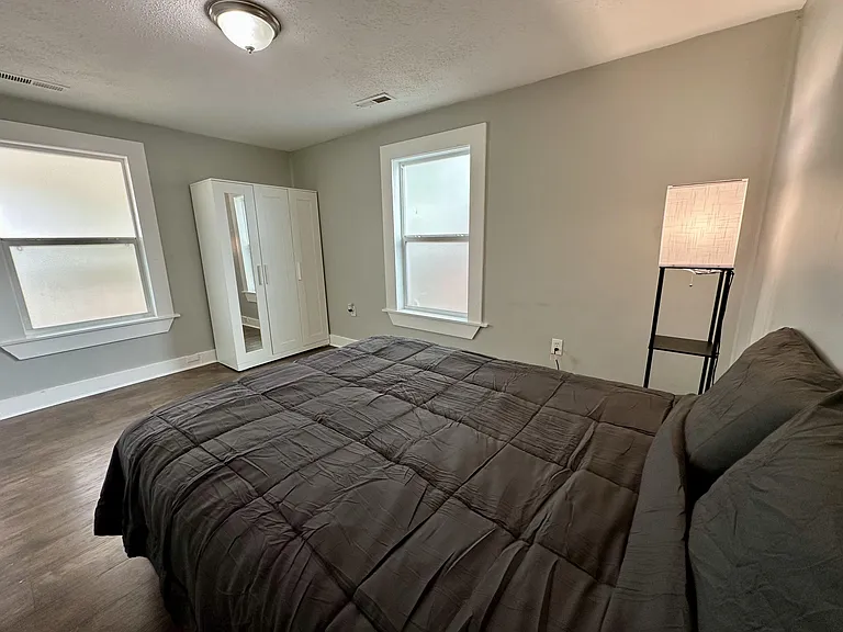 Furnished bedroom with two windows, wood-style flooring, and a wardrobe closet for convenient storage.