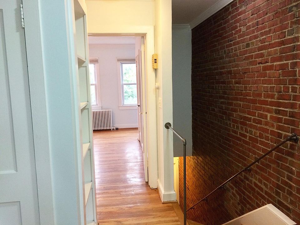 Exposed brick wall and stairs leading to apartment from front door.