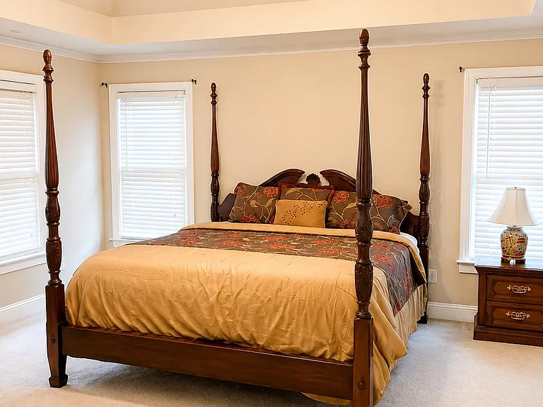 Spacious bedroom with a vaulted ceiling, ceiling fan, and multiple windows with blinds for privacy and natural light.