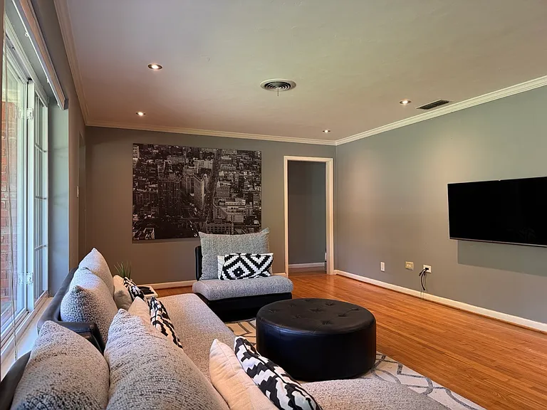 A view of the main living space showcasing a dramatic accent wall, ideal for large statement artwork, alongside expansive picture windows that look out to the front yard.