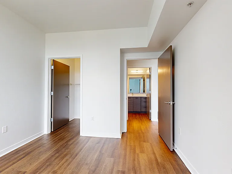 Spacious apartment bedroom with large closet and wood-style flooring.