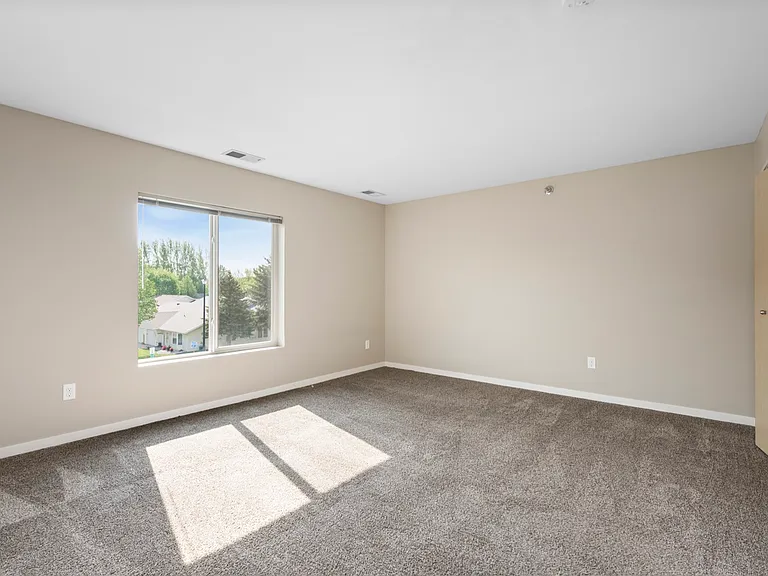 Bright and spacious bedroom with large window offering a serene view, plush carpeting, and neutral walls. Bright and spacious bedroom with large window offering a serene view, plush carpeting, and neutral walls.