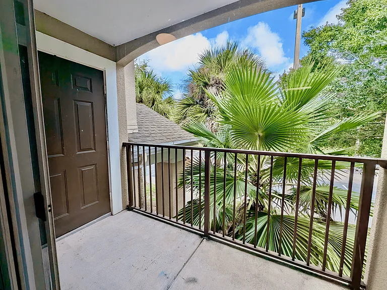 Screened apartment balcony with lush palm views, offering a tranquil outdoor space to relax and unwind.