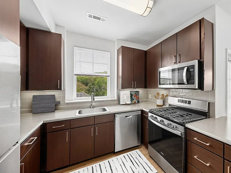 Updated Finishes kitchen with stainless steel appliances, espresso cabinetry, tile backsplash, laminate countertops, and hard surface flooring