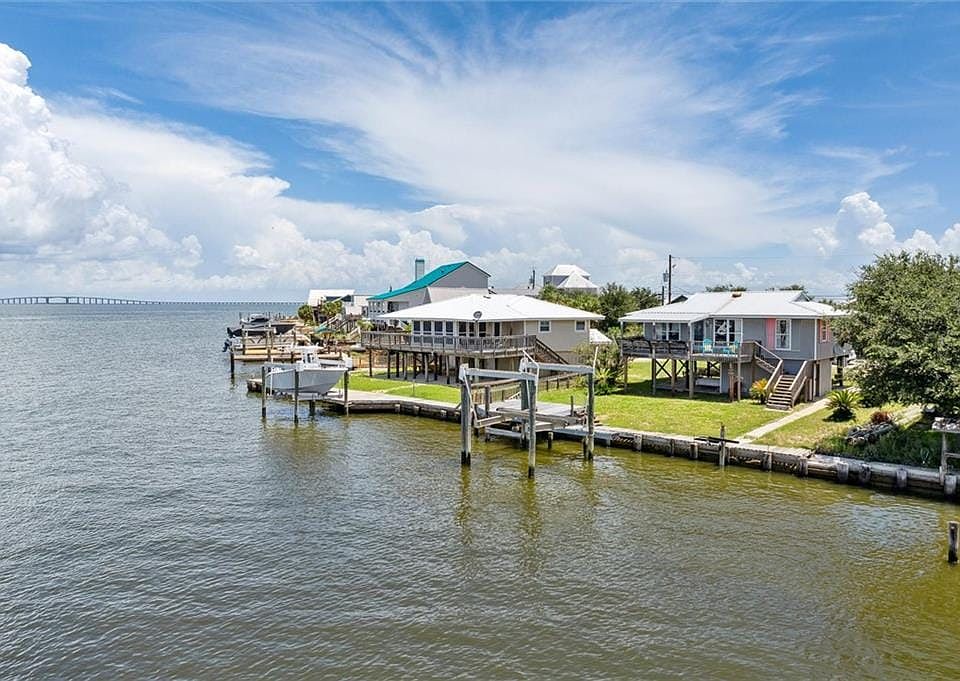 Dock area with boat lift, a deck with water view, and stairs