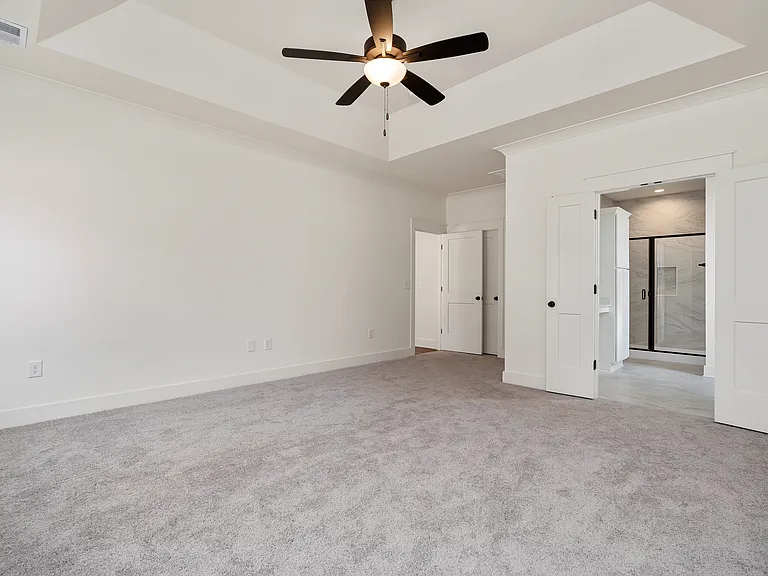 A private main suite in nestled at the back of the home featuring a trey ceiling and large walk-in closet upgraded by Closet Pro.