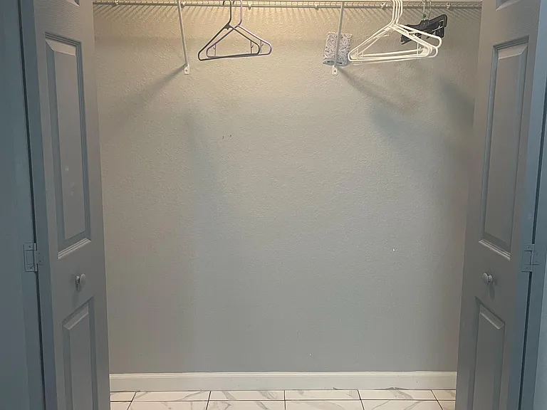 Spacious walk-in closet with wire shelving and hanging rod, offering easy organization and extra storage space.
