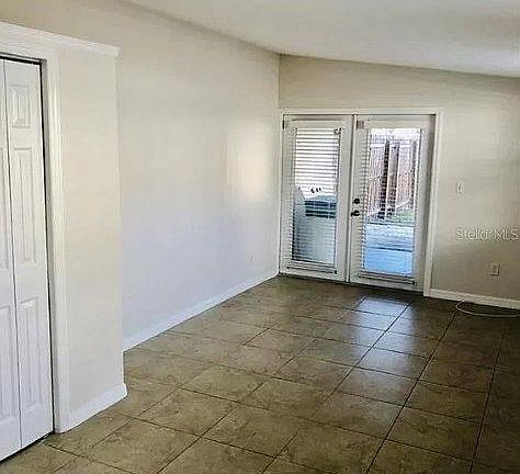 Living/bedroom area. Closet door can be seen to the left and the double glass doors leading outdoors.