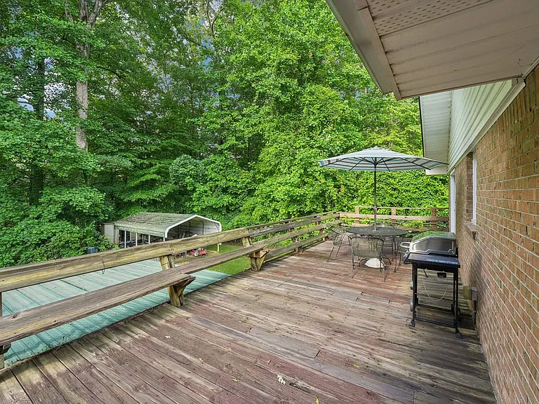 A peaceful back deck tucked into the trees, offering a storybook outdoor escape where morning coffee, quiet afternoons, and golden evening gatherings feel beautifully at home.